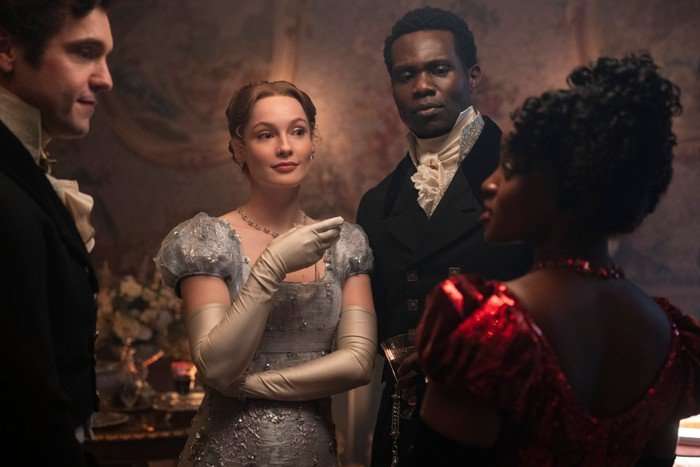 Bridgerton-s4-Francesca-Michaela Hannah Dodd as Francesca Bridgerton, Victor Alli as John Stirling, Masali Baduza as Michaela in Bridgerton standing around at a party, chatting and holding drinks.