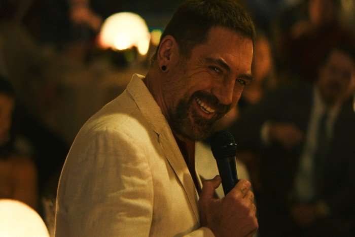 CapeFear_101_F0163533F_f Javier Bardem in Cape Fear, wearing a white jacket and smiling, holding a microphone.