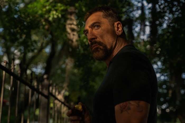 Cape_Fear_Photo_010203 Javier Bardem’s Max Cady stands by a wrought-iron fence in a shadowy, tree-lined outdoor scene from Cape Fear (2026), holding a half-eaten apple and staring intensely off-screen.
