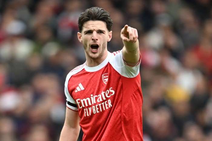Declan Rice, in red and white Arsenal kit, shouts as he points with his left hand.