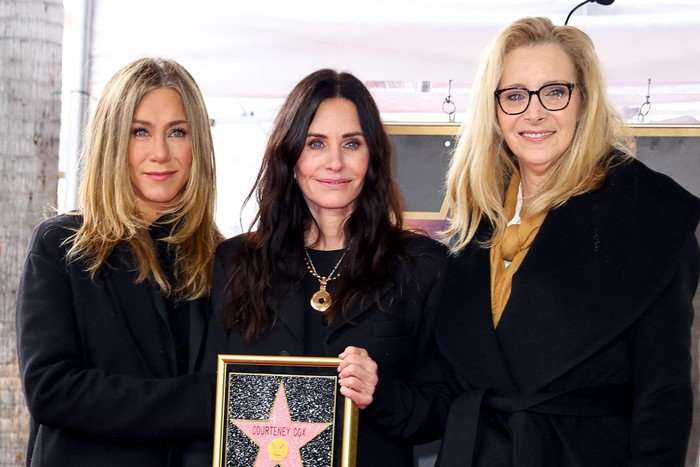 Jennifer Aniston, Courteney Cox and Lisa Kudrow standing together, with Cox holding her star on the Hollywood Walk of Fame as it is officially instated