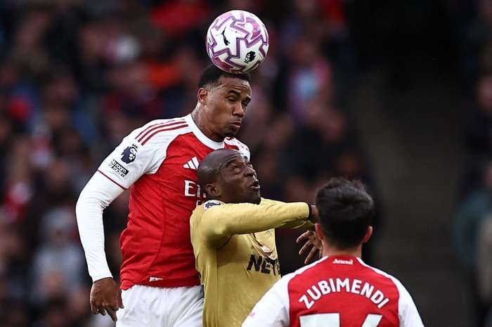 Gabriel Gabriel, in red and white Arsenal football kit, rises above Jean-Philippe Mateta, in gold Crystal Palace football kit, to header a football.