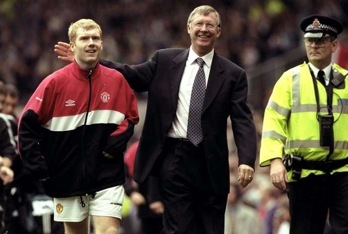 Alex Ferguson and Paul Scholes Paul Scholes and Sir Alex Ferguson walking off the pitch after a game, both smiling, Scholes in a red, white and black jacket and Ferguson in a dark suit.