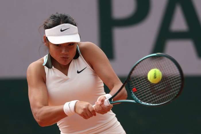 French Open 2026 Emma Raducanu Tennis player Emma Raducanu, in a white dress and cap, hits a backhand on the court at the French Open.