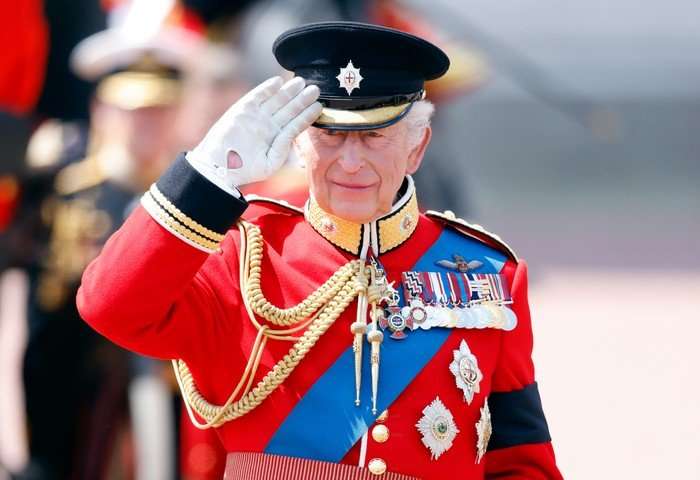 Trooping The Colour 2025 King Charles III stood wearing regal attire, making a salute to his head.