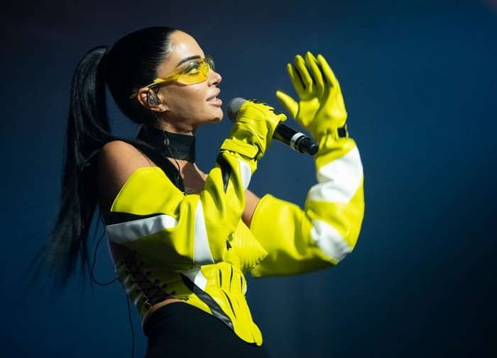 Manchester Pride 2025 - Sunday Tulisa performing on stage looking up as she holds onto a microphone.