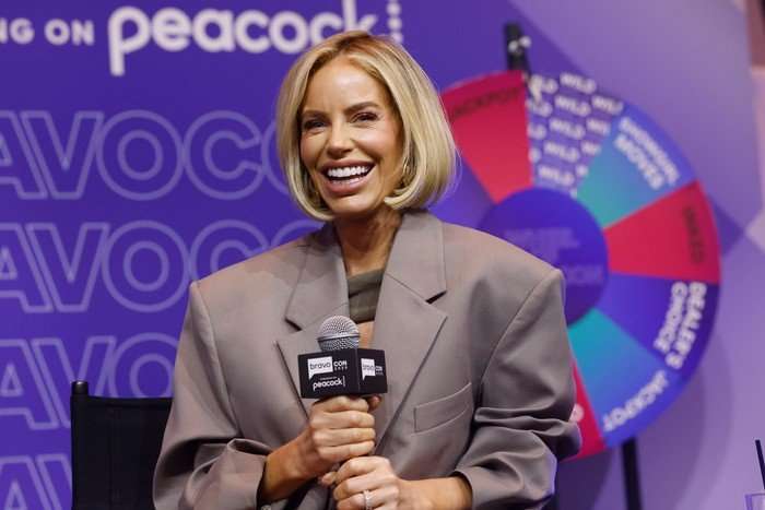 BravoCon Bravoverse Live Stage Caroline Stanbury holding a microphone with both hands and smiling ahead.