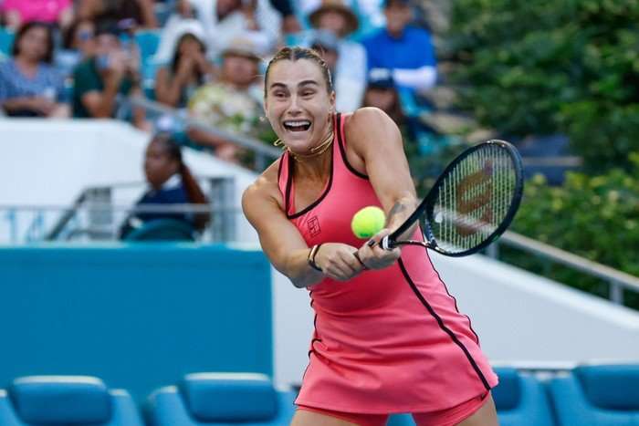 Aryna Sabalenka Tennis player Aryna Sabalenka, in a pink Nike tennis dress, hits a backhand on court at the Miami Open.