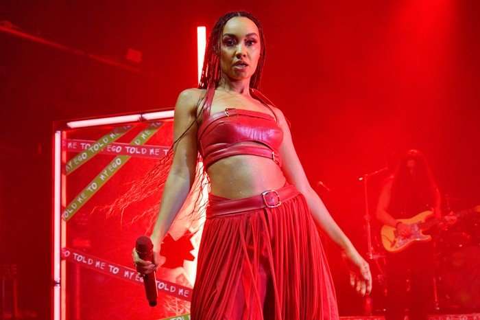 Leigh-Anne Pinnock wearing a red bandeau top and trousers, stood on stage.