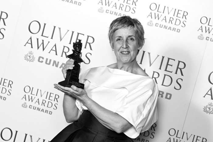 Julie Hesmondhalgh posing with an Olivier award, smiling ahead and wearing a white and black gown.