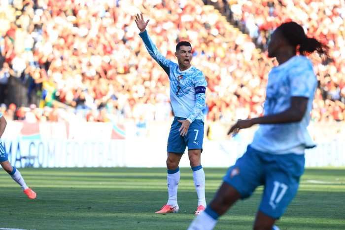 Cristiano Ronaldo Portugal forward Cristiano Ronaldo, in a white and blue football kit, shouts and holds his hand up on the pitch.