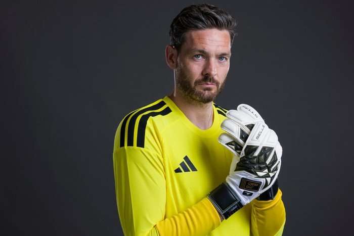 Craig Gordon Scotland goalkeeper Craig Gordon, in yellow, adjusts his gloves as he looks at the camera in front of a grey background.