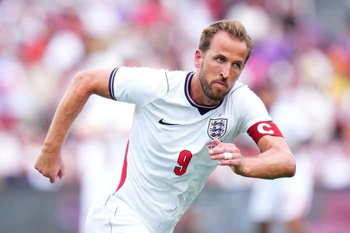 Harry Kane England captain Harry Kane, in white and red football kit, runs on the pitch.