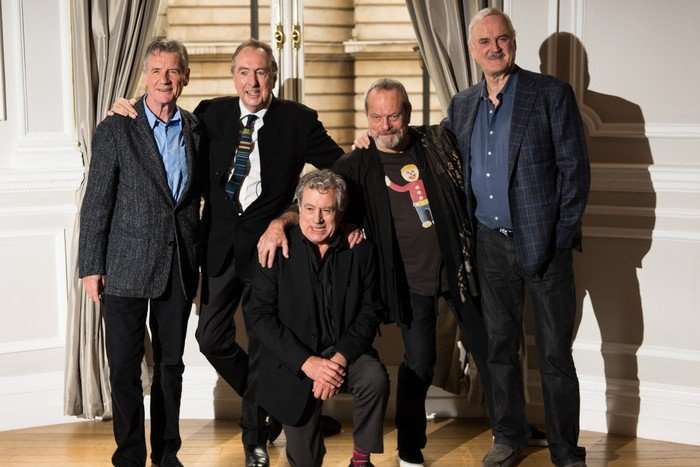 GettyImages-451034173 Michael Palin, Eric Idle, Terry Jones, Terry Gilliam and John Cleese at the Monty Python Reunion announcement in 2013, stood together, smiling at the camera. Jones is crouched down in the centre while the others are stood around him.