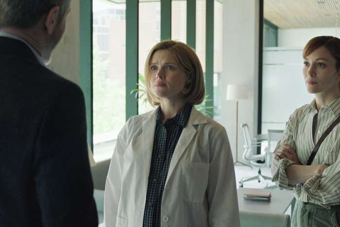 I Will Find You Erin Richards as Cheryl Dreason in I Will Find You standing in her lab, wearing her white coat and looking worried as she faces someone. She stands next to Britt Lower as Rachel Mills.