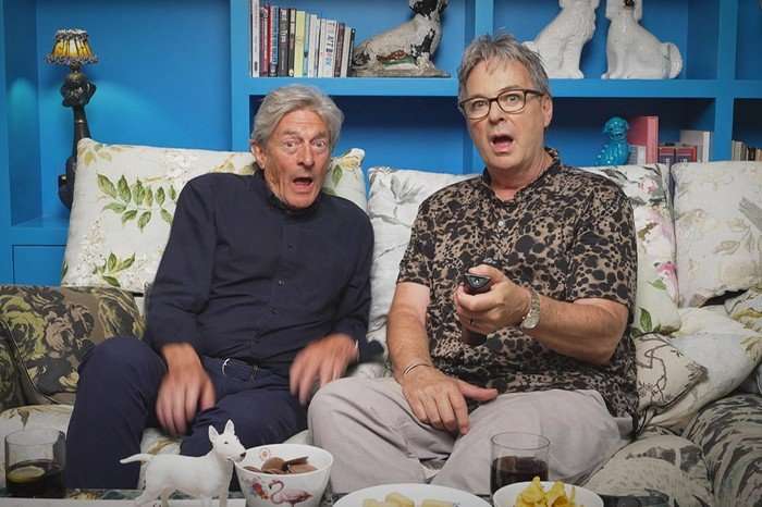 Nigel Havers and Julian Clary sat down next to each other on a sofa, looking surprised.