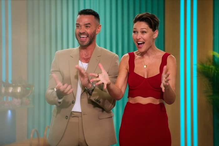 Love_Is_Blind__UK_u_S2_E1_00_04_41_05 copy Matt and Emma Willis stood next to each other, smiling ahead as they clap.