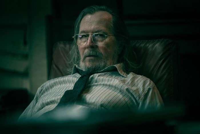 SlowHorses_602_00120F Gary Oldman in Slow Horses, slumped in a chair and looking at the camera.