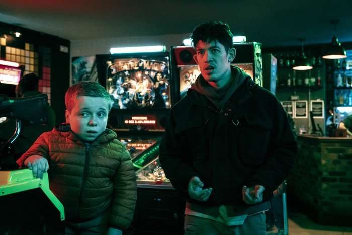 SlowHorses_603_01654F Christopher Chung and Lenny Rush in Slow Horses, stood in front of arcade games, looking worried.