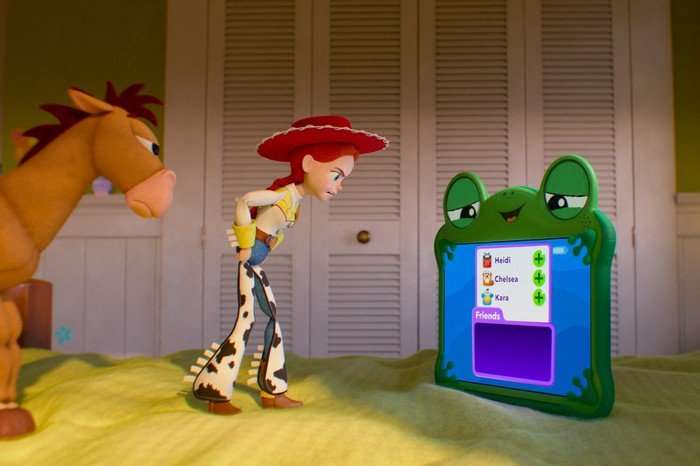 TOY STORY 5 A green frog tablet is on a bed while Jessie the cowgirl toy and her toy horse Bullseye, look at her angrily.