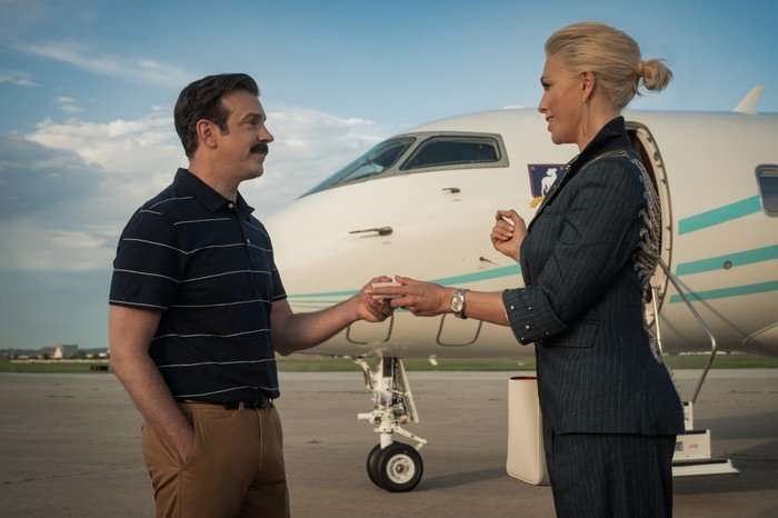 Jason Sudeikis and Hannah Waddingham star in Ted Lasso season 4; they are seen here on a runway, with a private jet in the background behind them