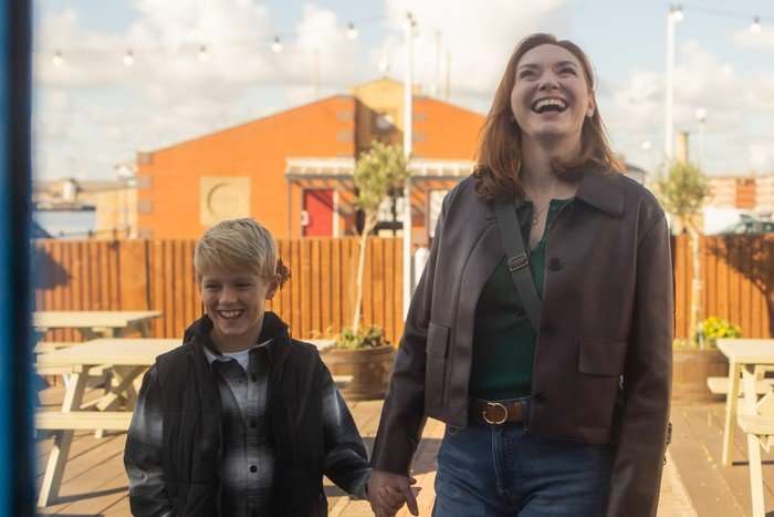 Eleanor Tomlinson as Amanda Blakefield holding James Younger as Luke Brent's hand and smiling.