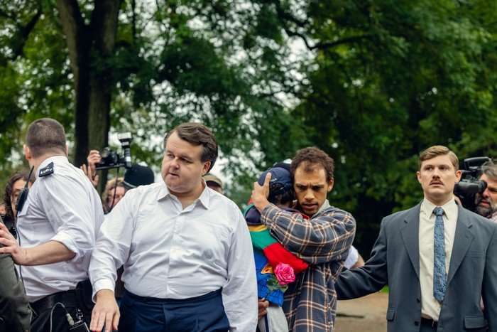 James Dryden as DC Paul Miller, Jordan Bolger as Andr&eacute; Hanscombe, Jonathan Pointing as DC Nick Sparshatt in The Witness navigating through a crowd of press in a park.