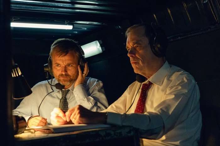 Neil Maskell as DI Keith Pedder and Kevin Eldon as DCI Mick Wickerson in The Witness sitting in the bank of a surveillance van and listening into something via headphones.