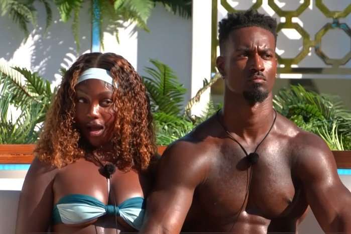 love-island-all-stars-2026 Leanne and Scott sat together by the fire pit making shocked expressions.