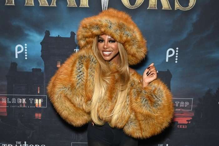the-traitors-US-candiace-dillard-bassett Candiace Dillard Bassett smiling ahead wearing a brown faux fur jacket and matching oversized faux fur hat.