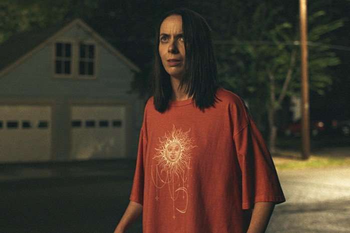Widows_Bay_Photo_010805 Kate O'Flynn as Patricia in Widow's Bay episode 8. She's wearing an oversized red T-shirt and is standing outside in the street in darkness.