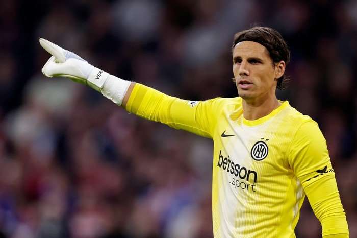 Yann Sommer, in yellow Inter Milan goalkeeping kit and white goalkeeper gloves, points with his right hand.