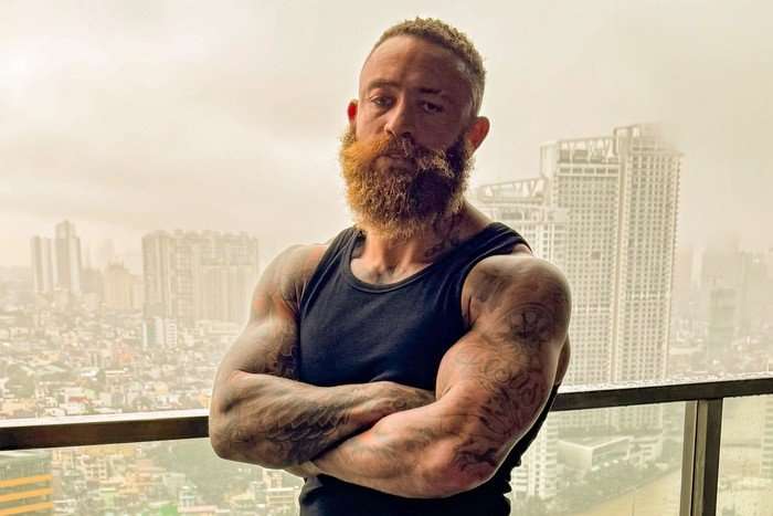 ashley-cain Ashley Cain stood on a balcony looking ahead with his arms folded over his chest.