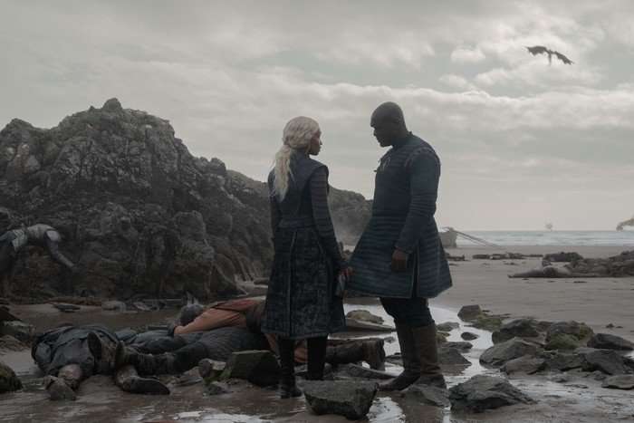 Bethany Antonia as Lady Baela Targaryen and Abubakar Salim as Alyn of Hull stand on shoreline in House of the Dragon season 3.