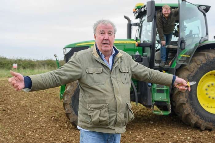 clarksons-farm (4) Jeremy Clarkson stood in front of a large green tractor with his hands spread outwards.