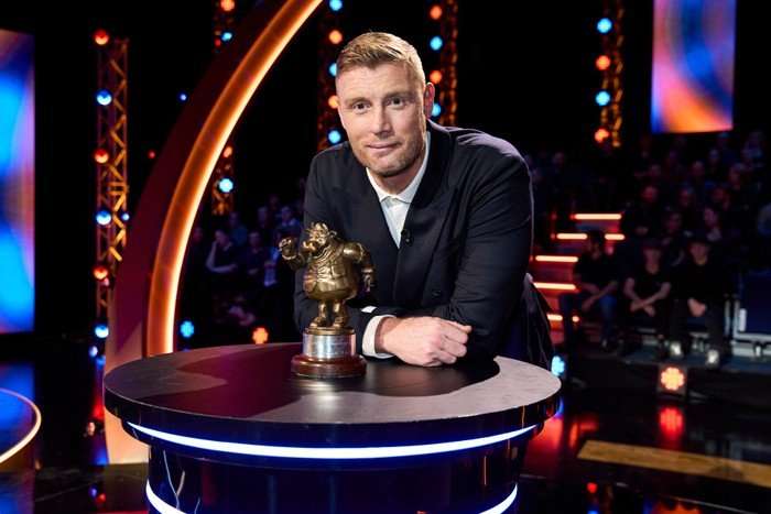 Freddie Flintoff hosting Bullseye. Freddie Flintoff hosting Bullseye, posing with the show's iconic trophy on a brightly lit stage.
