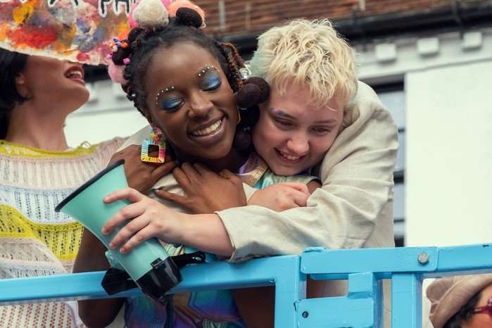 heartstopper-forever-tara-darcy Tara and Darcy lovingly embrace while at a Pride parade in a scene from Heartstopper Forever