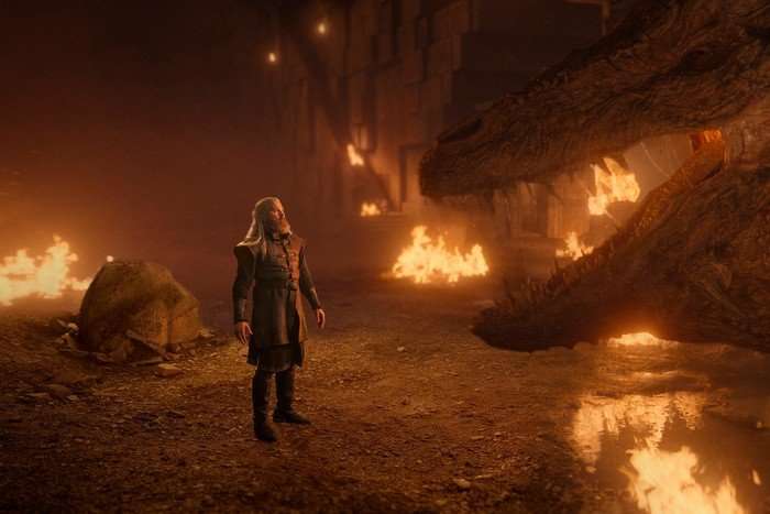 kieran-bew Kieran Bew as Hugh Hammer stares up at the dragon Vermithor amid fiery debris in House of the Dragon.