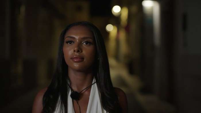 Love Island S13 Namibia wearing a white dress, walking down looking seriously.