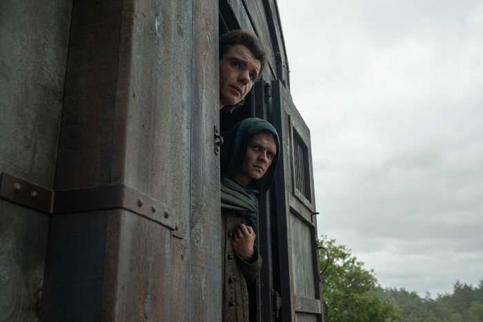 Matthew Needham as Lord Larys Strong and Tom Glynn-Carney as King Aegon II Targaryen sticking their heads out of a carriage in House of the Dragon season 3.
