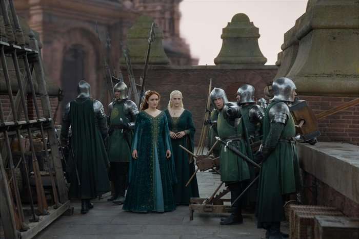 Olivia Cooke as Alicent Hightower and Phia Saban as Helaena Targaryen approach guards on the battlements in House of the Dragon season 3.