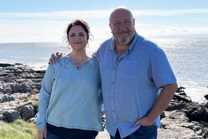 Ruth Jones and Steve Speirs photographed smiling shoulder-to-shoulder on a sunny clifftop