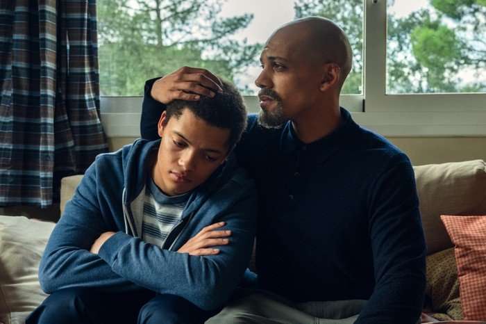 Max Fincham as Alex Hanscombe leaning on Jordan Bolger as Andr&eacute; Hanscombe while sitting on a bed in The Witness.