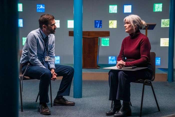 571862,TITLE:TIME - Series 3 David Tennant and Siobhan Finneran star in Time season 3; their characters are sat in a meeting room, with colourful windows in the background behind them