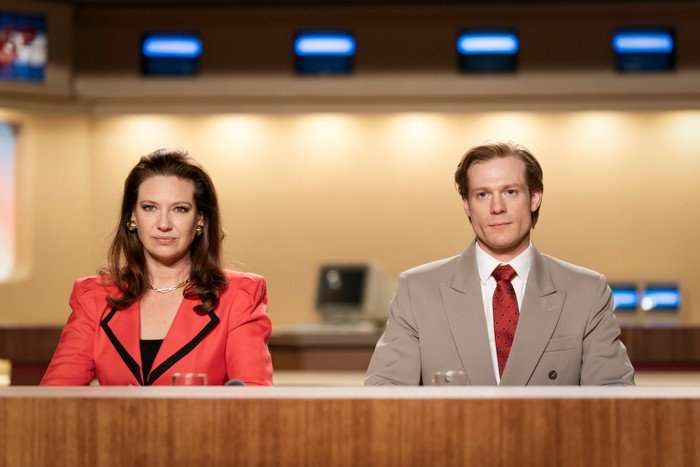 The Newsreader S2 Anna Torv as Helen Norville and Sam Reid as Dale Jennings in The Newsreader sat at a desk