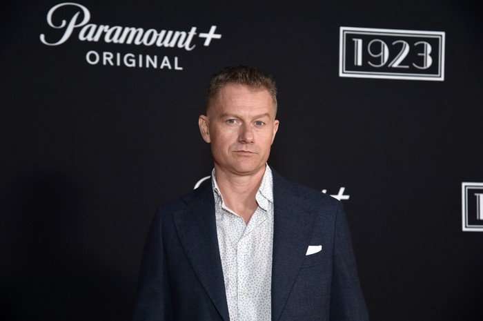 "1923" LA Premiere Screening & After Party James Badge Dale, wearing a jacket and open neck shirt and stood in front of a black backdrop.