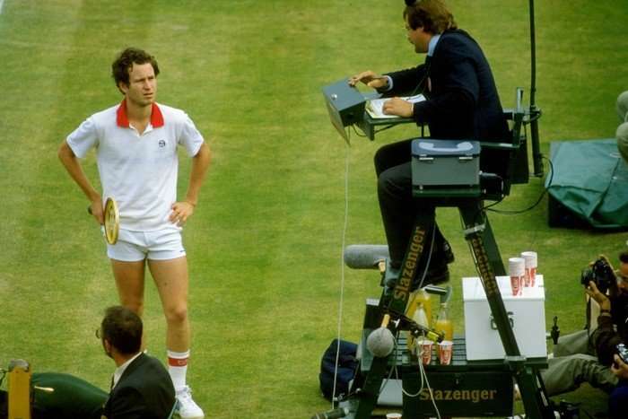 John McEnroe Tennis player John McEnroe, in all white, argues with an umpire sat on a high chair at Wimbledon.