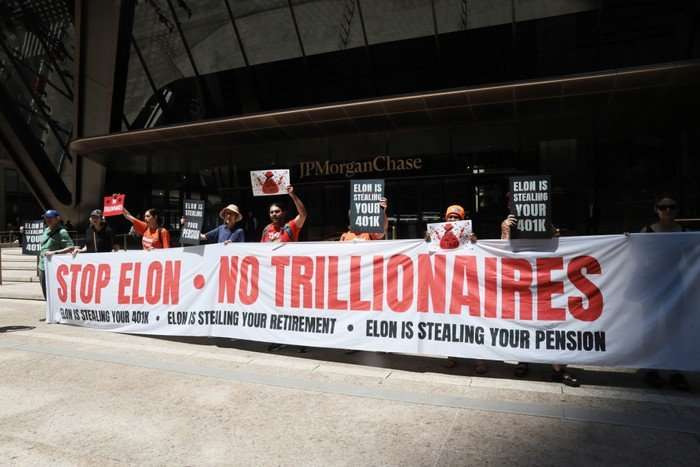 Protesters Demonstrate Against Elon Musk And The SpaceX IPO Outside Chase Bank Headquarters A line of protesters with a banner saying Stop Elon - No Trillionaires.
