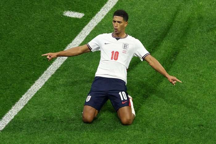 World Cup 2026 in England midfielder Jude Bellingham, in white and blue football kit, knee slides on the pitch at World Cup 2026.