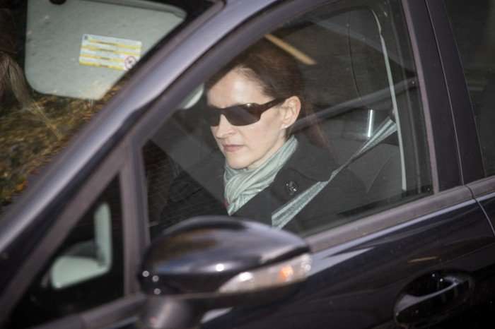 Victoria Cilliers in a car with sunglasses on, a black jacket and grey scarf looking ahead.